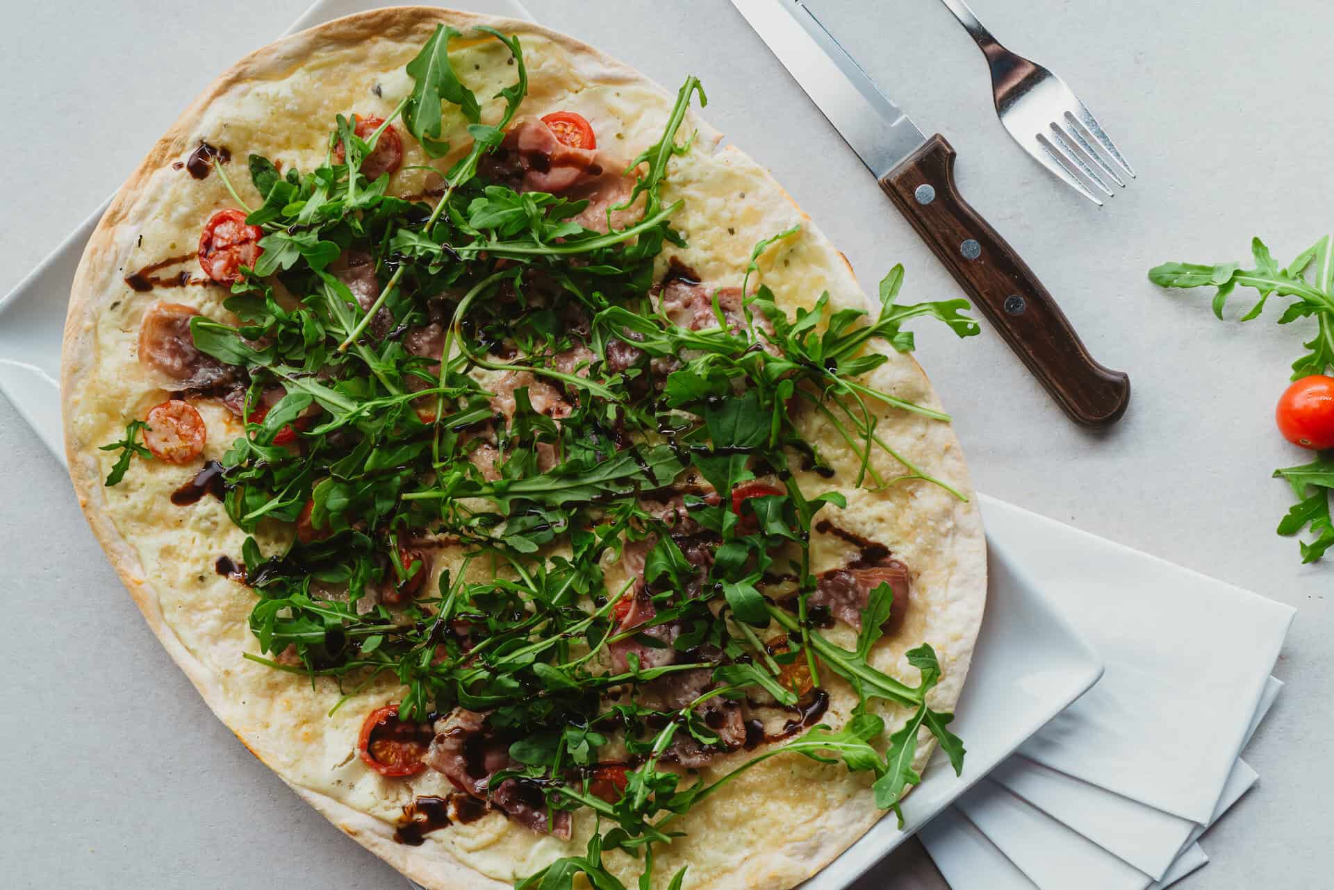Fresh pizza with arugula and tomatoe