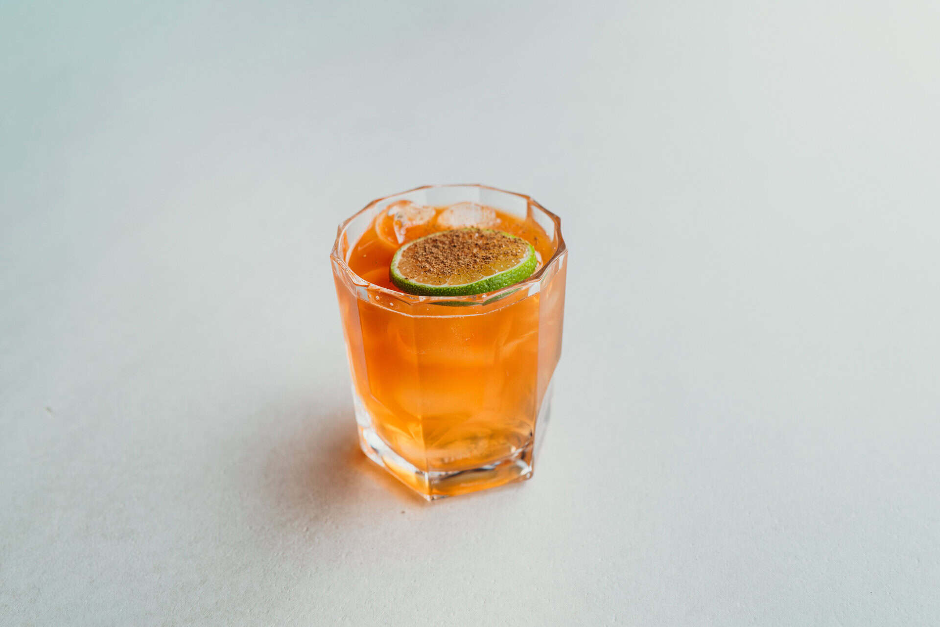 Refreshing cocktail with lime and orange slice in a glass at Bungalow 7.