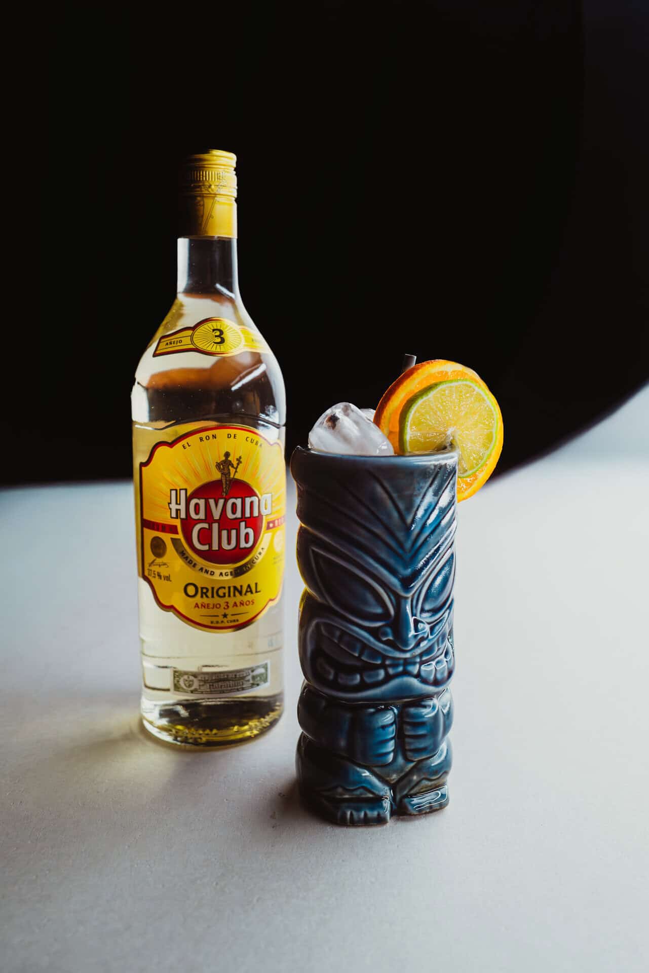 Tiki-style cocktail with lemon slice and Havana Club rum bottle.