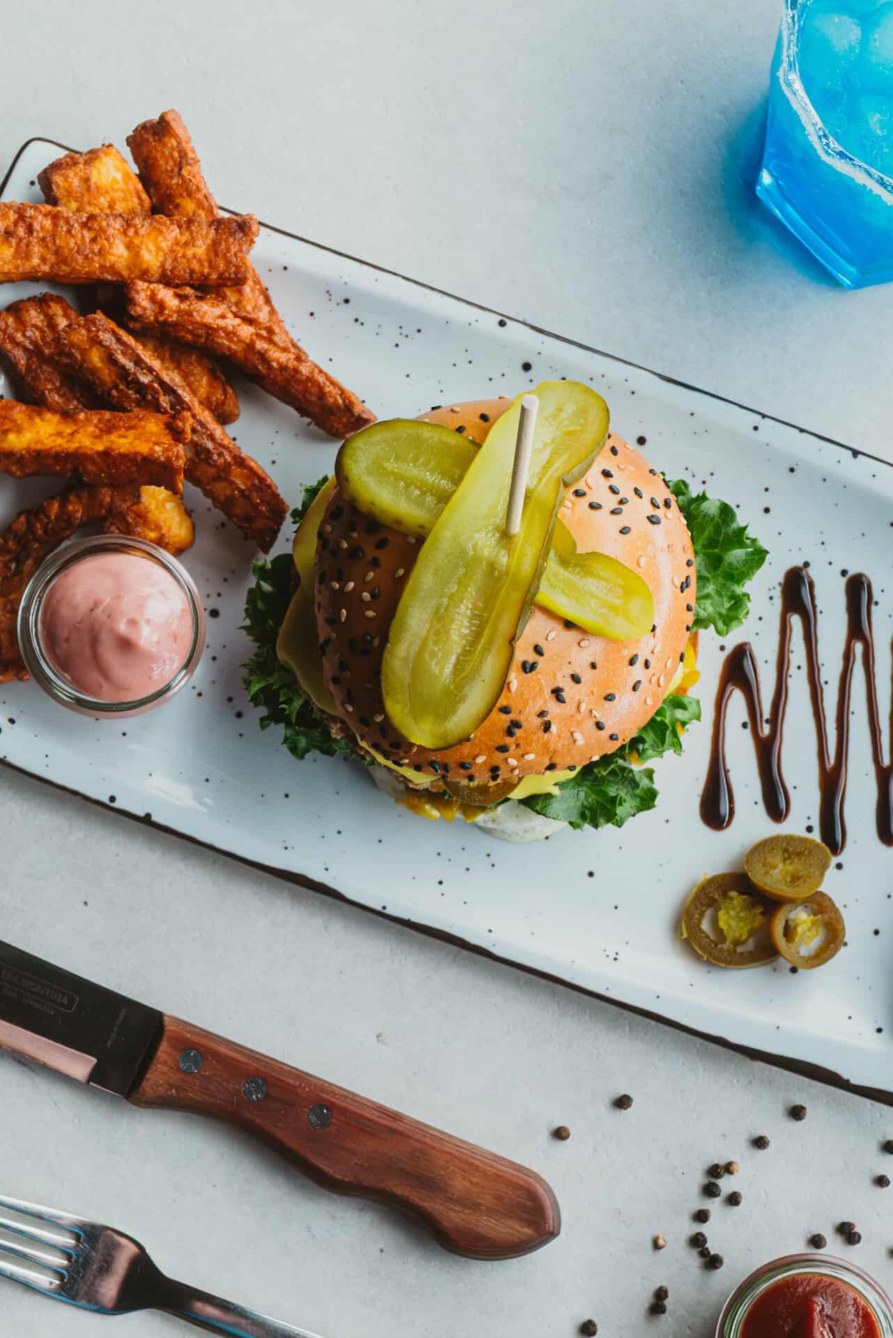 Burger mit Gewürzgurken, Pommes und Getränk im Bungalow 7.