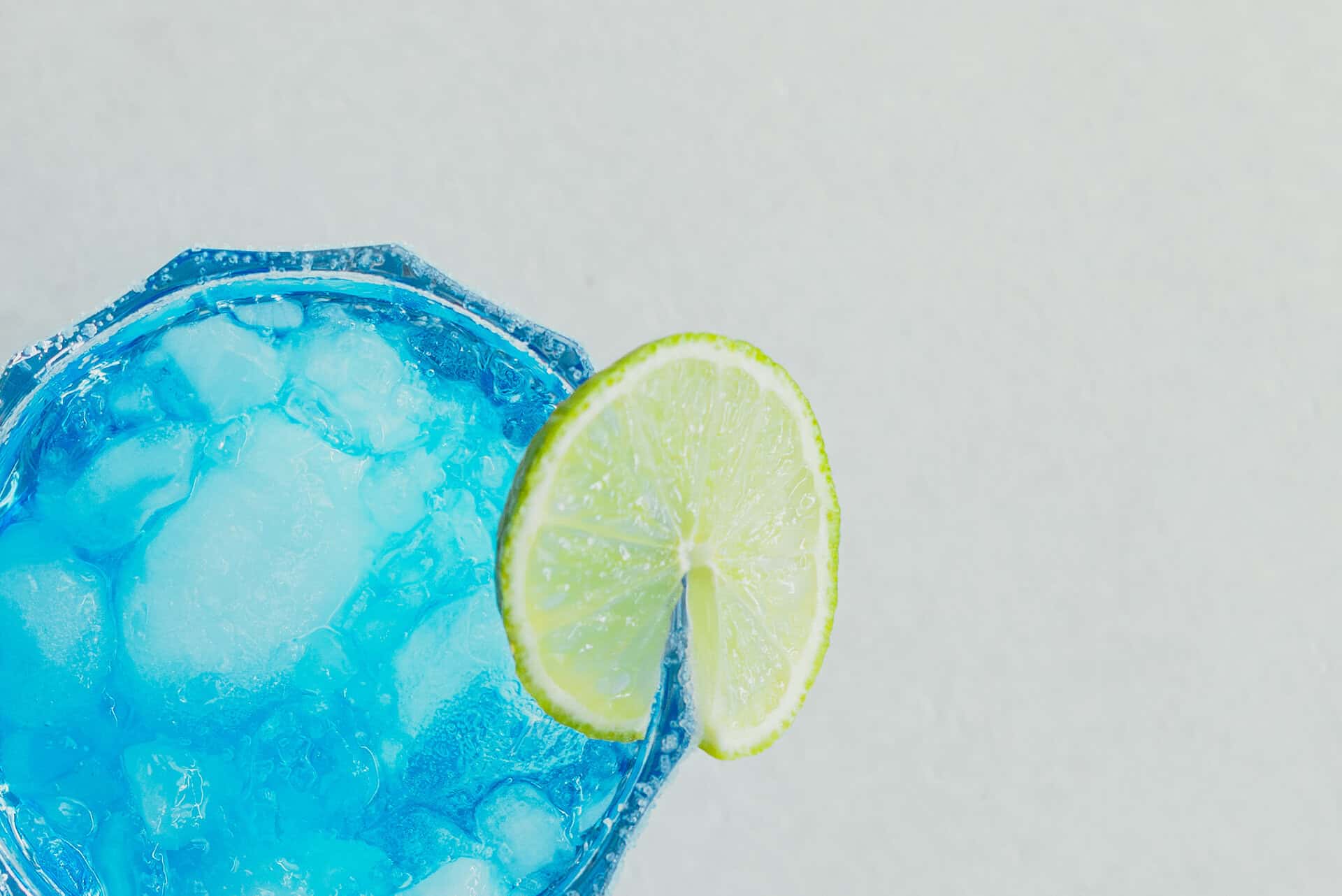 Buntes Getränk mit Limettenscheibe in einem Glas.